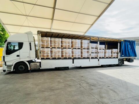 Camion con semirimorchio aperto carico di pallet imballati e pronti per la consegna.