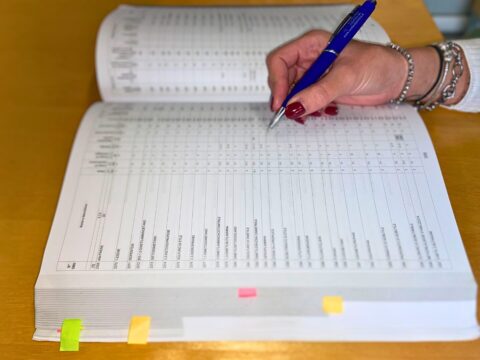 Mano che compila un registro ADR per la classificazione e gestione delle merci pericolose.