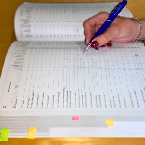 Mano che compila un registro ADR per la classificazione e gestione delle merci pericolose.